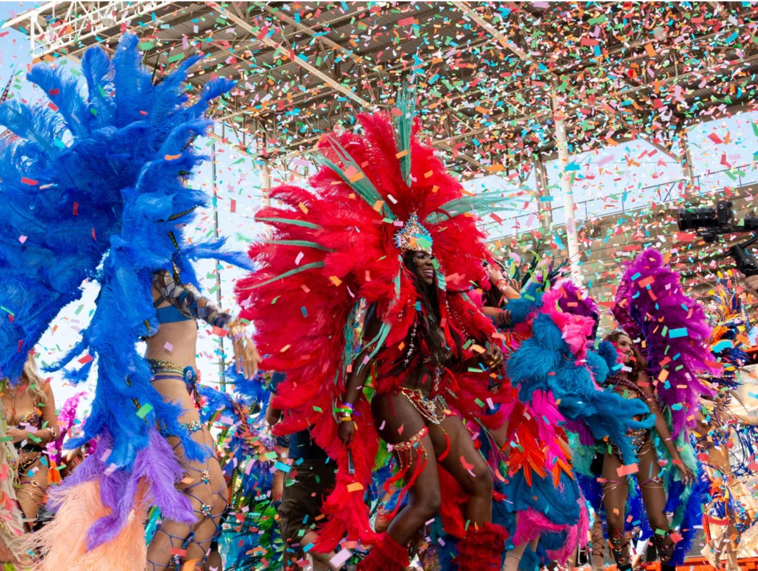 Masqueraders in feathered costumes under falling confetti